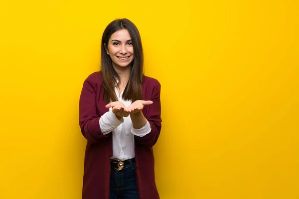 Jovem Mulher Sobre Parede Amarela Segurando Copyspace Imaginário Palma Mão — Fotografia de Stock