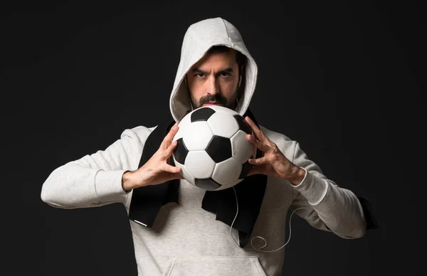 Sport uomo su sfondo scuro in possesso di un pallone da calcio — Foto Stock