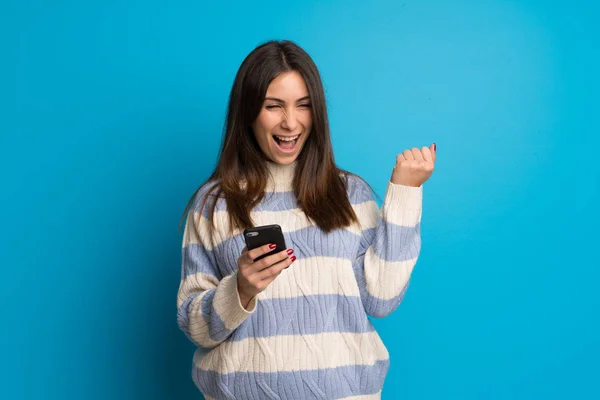 Junge Frau Über Blaue Mauer Feiert Sieg Mit Handy — Stockfoto