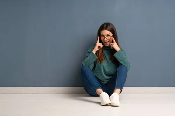Junge Frau Sitzt Mit Brille Auf Dem Boden Und Überrascht — Stockfoto