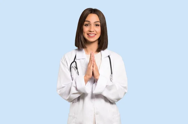 年轻的医生妇女保持手掌在一起 人要求的东西在被隔绝的蓝色背景 — 图库照片