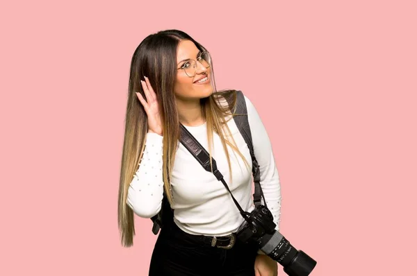Молодая Фотограф Женщина Слушает Положив Руку Ухо Изолированном Розовом Фоне — стоковое фото