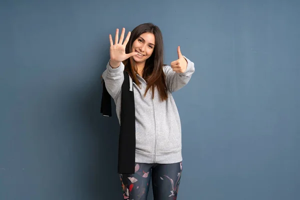Young sport woman counting six with fingers