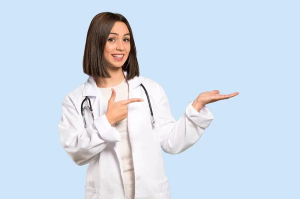 Young Doctor Woman Holding Copyspace Imaginary Palm Insert Isolated Blue — Stock Photo, Image