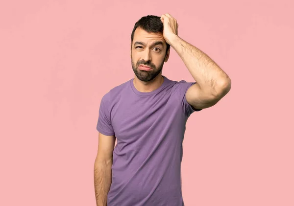 Handsome man with an expression of frustration and not understanding on isolated pink background