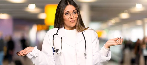 年轻的医生妇女在医院举起手来时产生疑问 — 图库照片