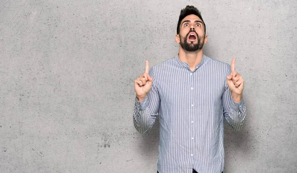 Elegante Hombre Con Camisa Sorprendida Apuntando Hacia Arriba Sobre Pared —  Fotos de Stock