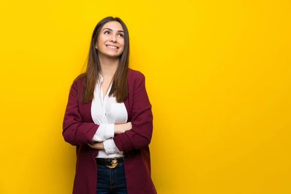 笑顔ながら見上げる黄色の壁を越えて若い女性 — ストック写真