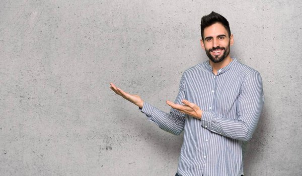 Elegant man with shirt extending hands to the side for inviting to come over textured wall