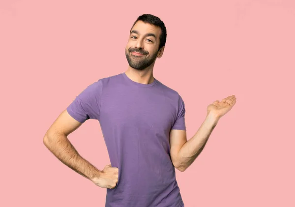 英俊的人拿着复制空间想象在手掌上插入一个广告在孤立的粉红色背景 — 图库照片