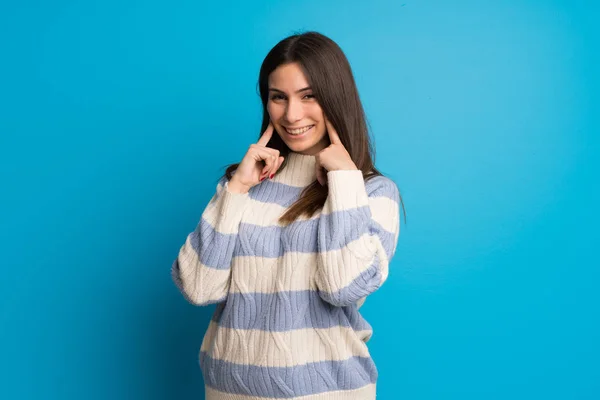 Young woman over blue wall smiling with a happy and pleasant expression