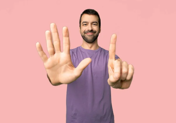 英俊的人计数六与手指在被隔绝的粉红色的背景 — 图库照片