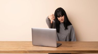 Genç kadın, onu laptop ile negatif ifade başparmak aşağı gösteren çalışma