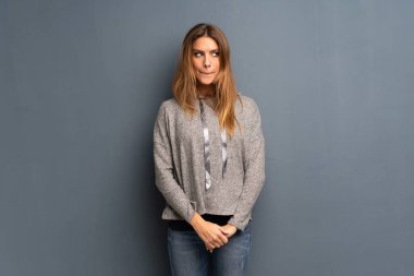 Sarışın kadın ile karıştırmayın yüz ifadesi ısırıkları dudak iken gri arka plan üzerinde