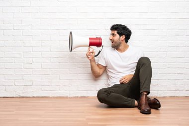Bir megafon ile bağırarak katta oturan genç adam