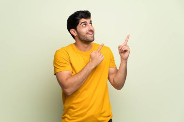 Pembe duvar üzerinde genç adam işaret parmağı ile gösteren ve yukarı bakıyor