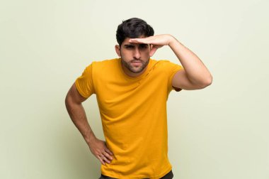 Bir şey bakmak için genç adam pembe duvar uzakta el ile seyir üzerinde