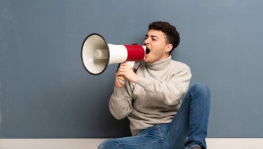 Bir megafon ile bağırarak katta oturan genç adam