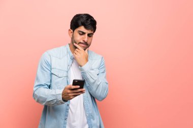 Pembe duvar düşünme ve bir mesaj gönderme üzerinde genç adam