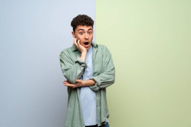 Genç adam şaşırttı ve doğru bakarken şok mavi ve yeşil arka plan üzerinde