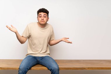 Genç adam masada oturan şüphe jest yapma