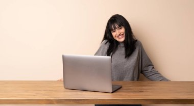 Gülümsediğini laptop ile çalışan genç kadın