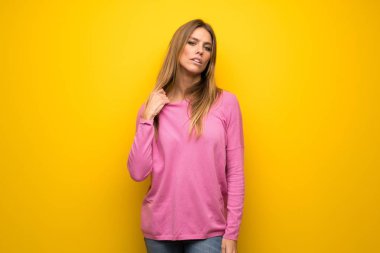 Yorgun ve hasta ifade ile sarı duvar üzerinde pembe kazak ile kadın