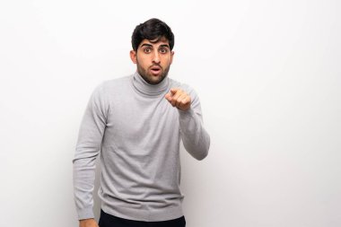 İzole beyaz duvar üzerinde genç adam şaşırttı ve ön işaret