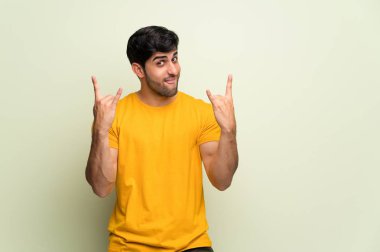 Pembe duvar üzerinde genç adam rock jest yapma