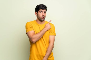 Pembe duvar üzerinde genç adam şaşırttı ve yan işaret