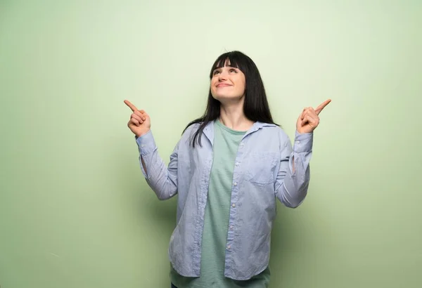 Молода Жінка Над Зеленою Стіною Вказує Індексний Палець Чудова Ідея — стокове фото
