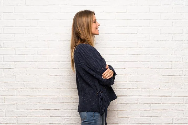 Blonde woman over brick wall in lateral position