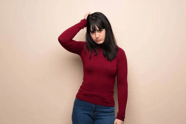 Young woman with red turtleneck with an expression of frustration and not understanding