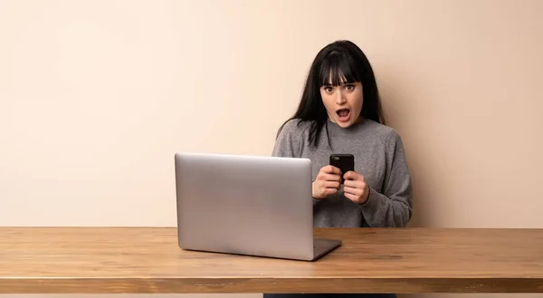 Jovem Mulher Trabalhando Com Seu Laptop Surpreendido Enviando Uma Mensagem — Fotografia de Stock