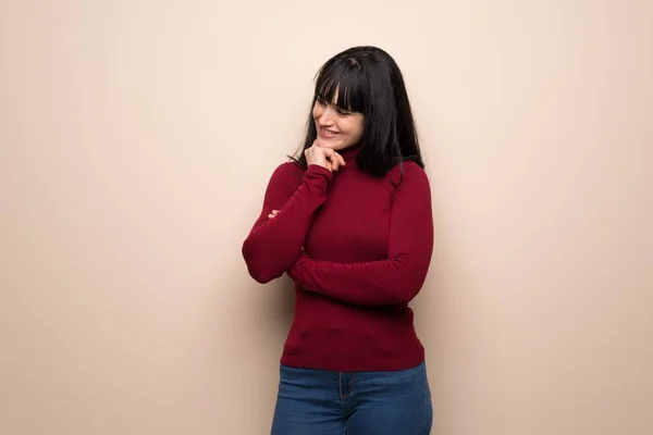 Young woman with red turtleneck looking to the side with the hand on the chin