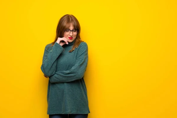Kobieta Okularach Żółty Ścianę Patrząc Dół Ręką Brodzie — Zdjęcie stockowe
