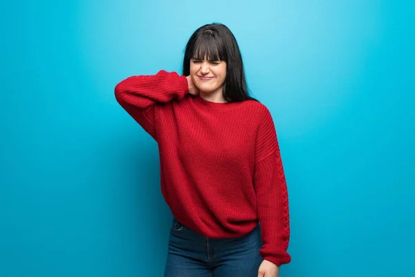 Woman with red sweater over blue wall with neckache