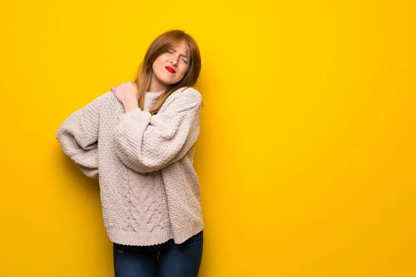 努力をしたために肩の痛みに苦しむ黄色い壁の上の赤毛の女性 — ストック写真