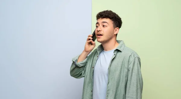 Mavi Yeşil Arka Plan Üzerinde Genç Adam Cep Telefonu Ile — Stok fotoğraf