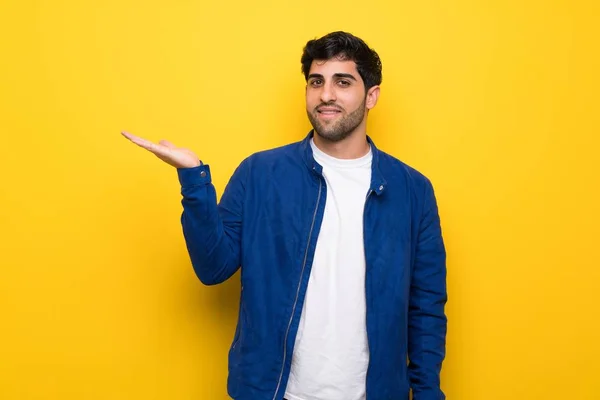 Homem Com Casaco Azul Sobre Parede Amarela Segurando Copyspace Imaginário — Fotografia de Stock