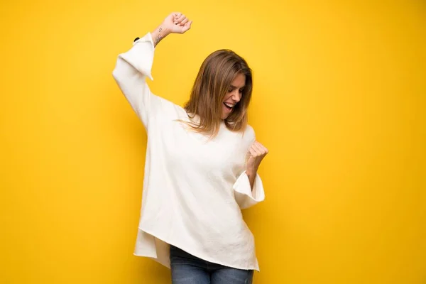 勝利を祝う黄色の壁を越えて金髪女性 — ストック写真