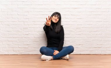 Kadın yerde oturan mutlu ve parmak ile üç sayma