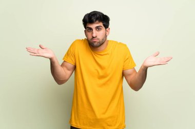 Eller ve omuzlar yükselterek pembe duvar üzerinden genç adam şüpheler