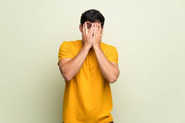 Genç adam üzerinde pembe duvar gözleri eller tarafından kapsayan ve parmaklara bakarak