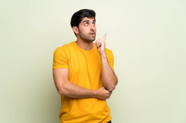 Parmak yukarı işaret eden bir fikir düşünme pembe duvar üzerinde genç adam