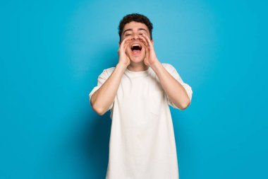 Mavi arka planda genç adam bağırmak ve bir şey duyurdu