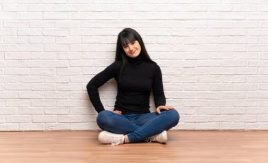 Yerde oturan kadın kalça ve gülümseyen kollar ile poz