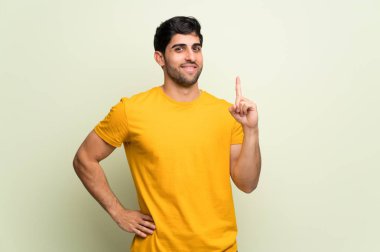 Pembe duvar üzerinde genç adam gösteren ve en iyi işareti bir parmak kaldırma