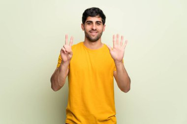 Parmak ile yedi sayma pembe duvar üzerinde genç adam