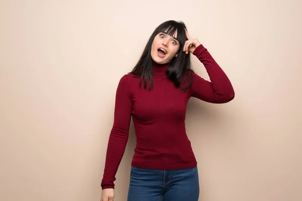 Young woman with red turtleneck has just realized something and has intending the solution